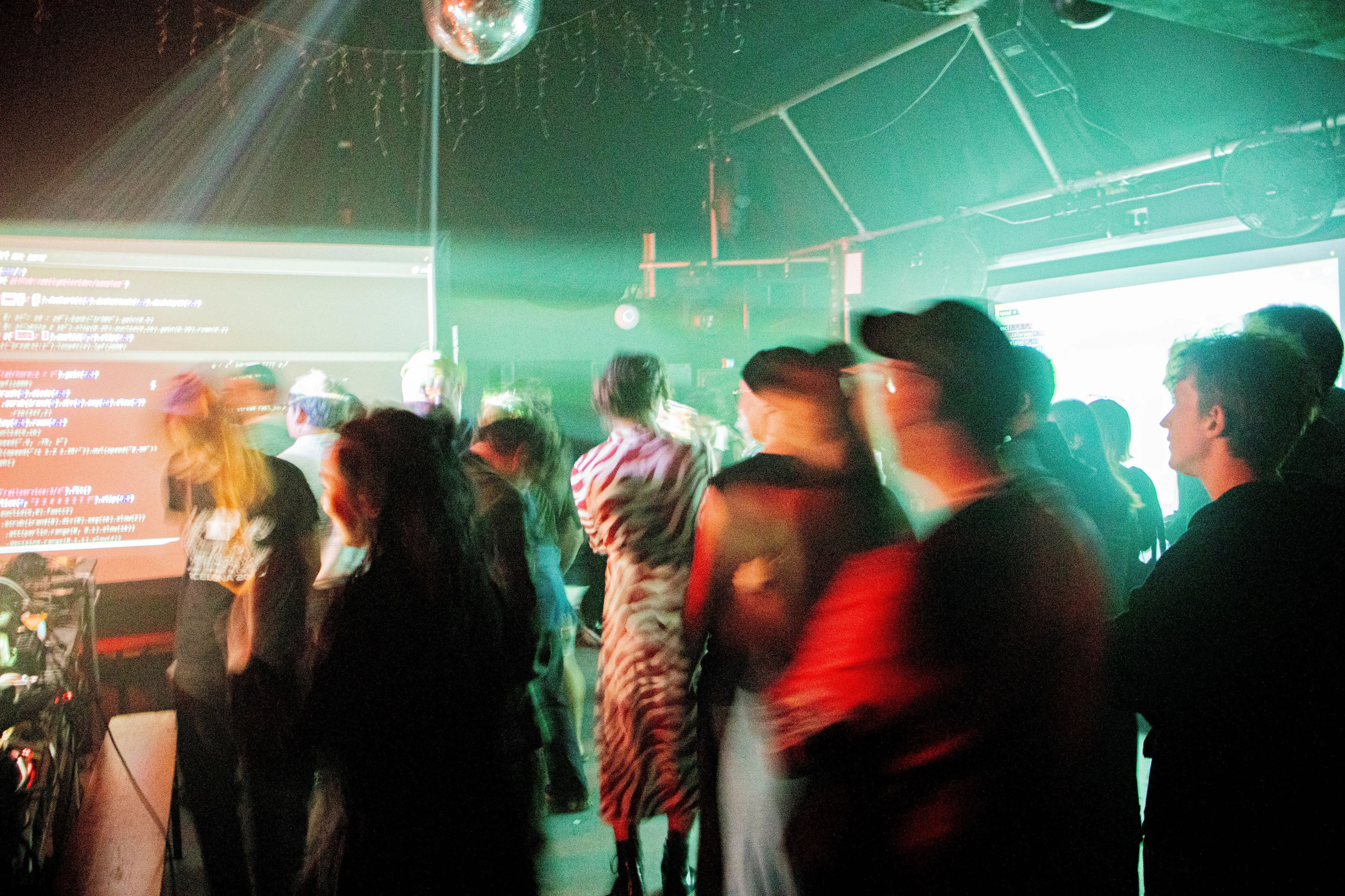 Indoor venue with projected visuals, audience and performers.